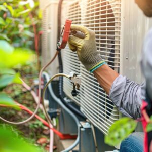 A gloved hand working on the electrical wiring of an outdoor AC condenser unit.