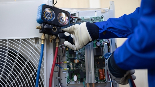 An HVAC tech adjusts an HVAC system