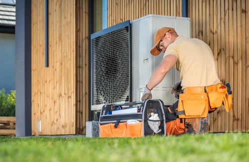 An HVAC tech works on an HVAC system outdoors